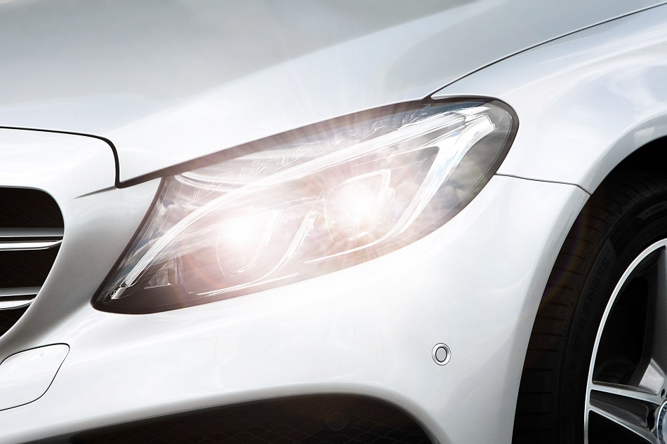 Headlight of a white Mercedes-Benz sedan